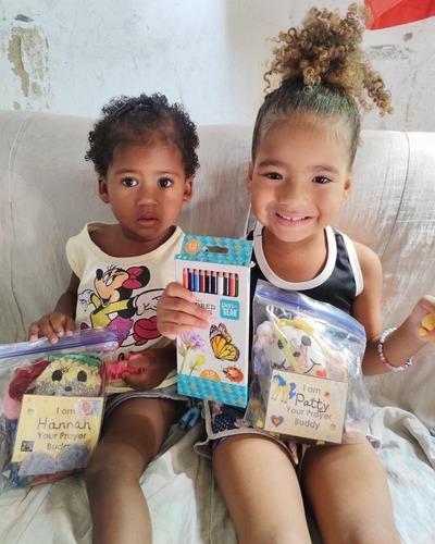 Two kids happily receiving a gift from Bags of Hope