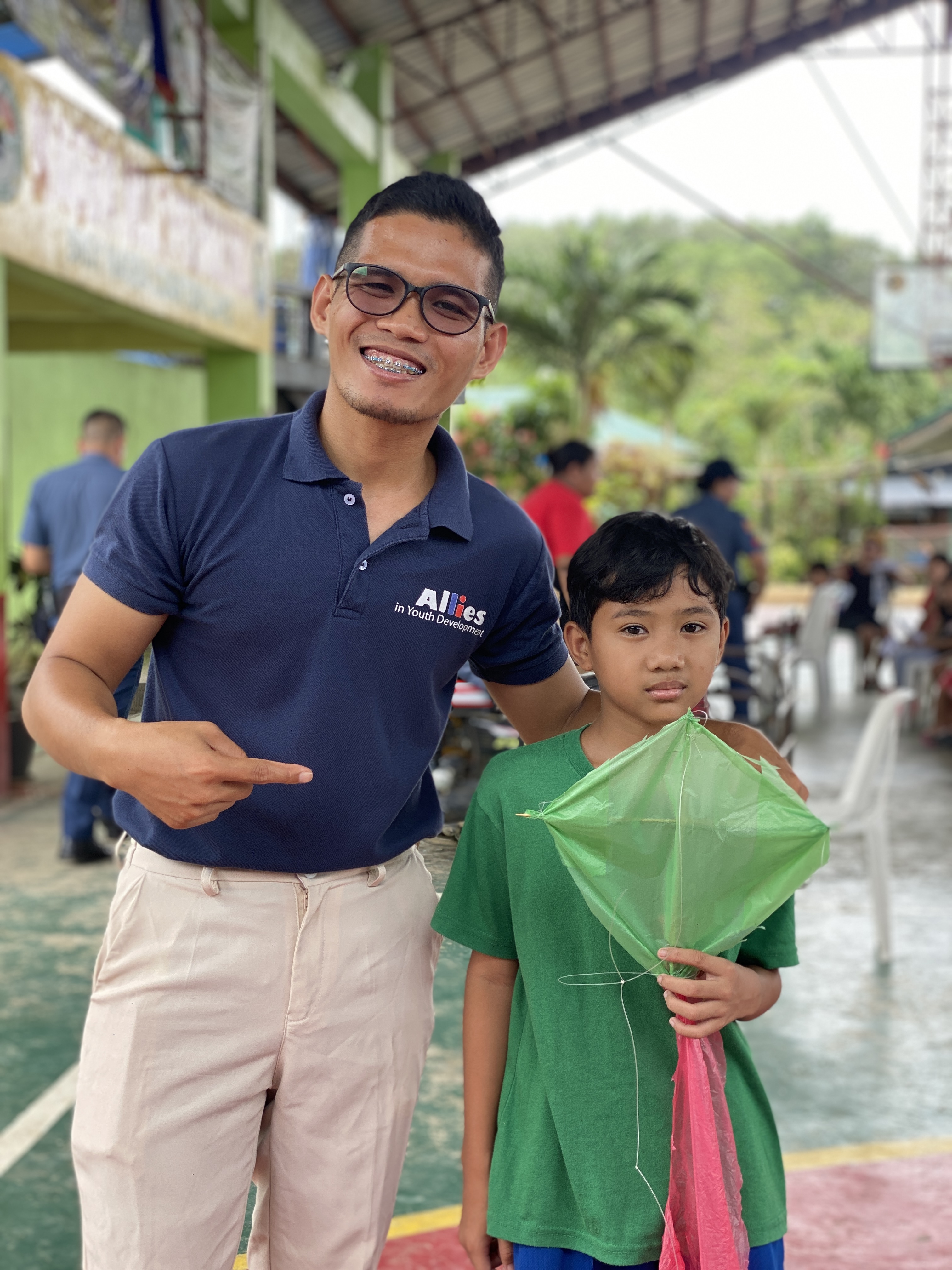 Allies mentor standing with child and supplies